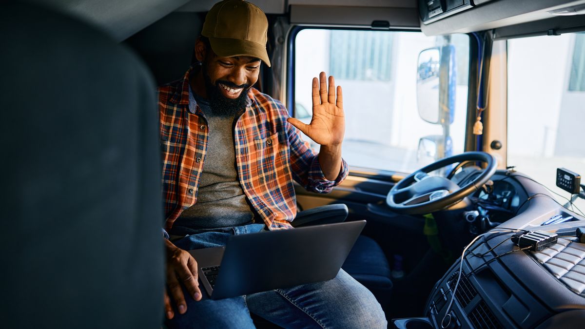 A truck driver reviewing information on a laptop in his cab